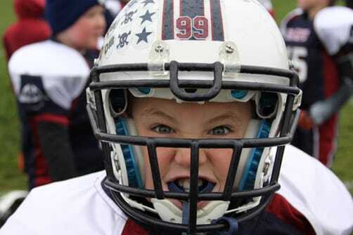 Young athlete wearing football helmet with mouth guard protection.