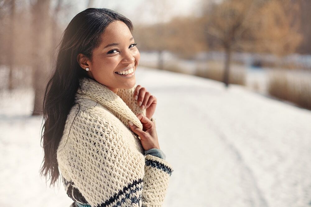 Young woman smiling outdoors in winter clothing in Corpus Christi.