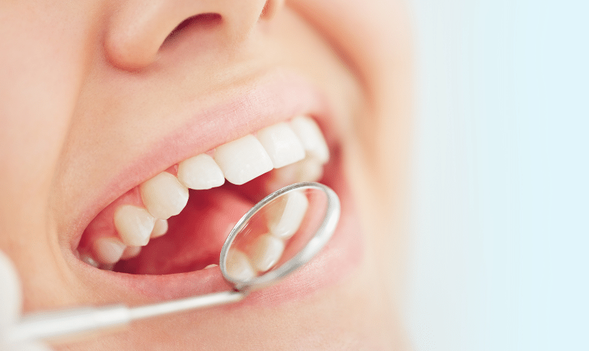 Child's bright smile with white teeth displayed during dental examination with mirror.