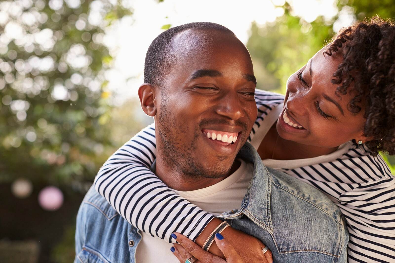 Happy couple smiling together outdoors, displaying healthy bright teeth and genuine joy.