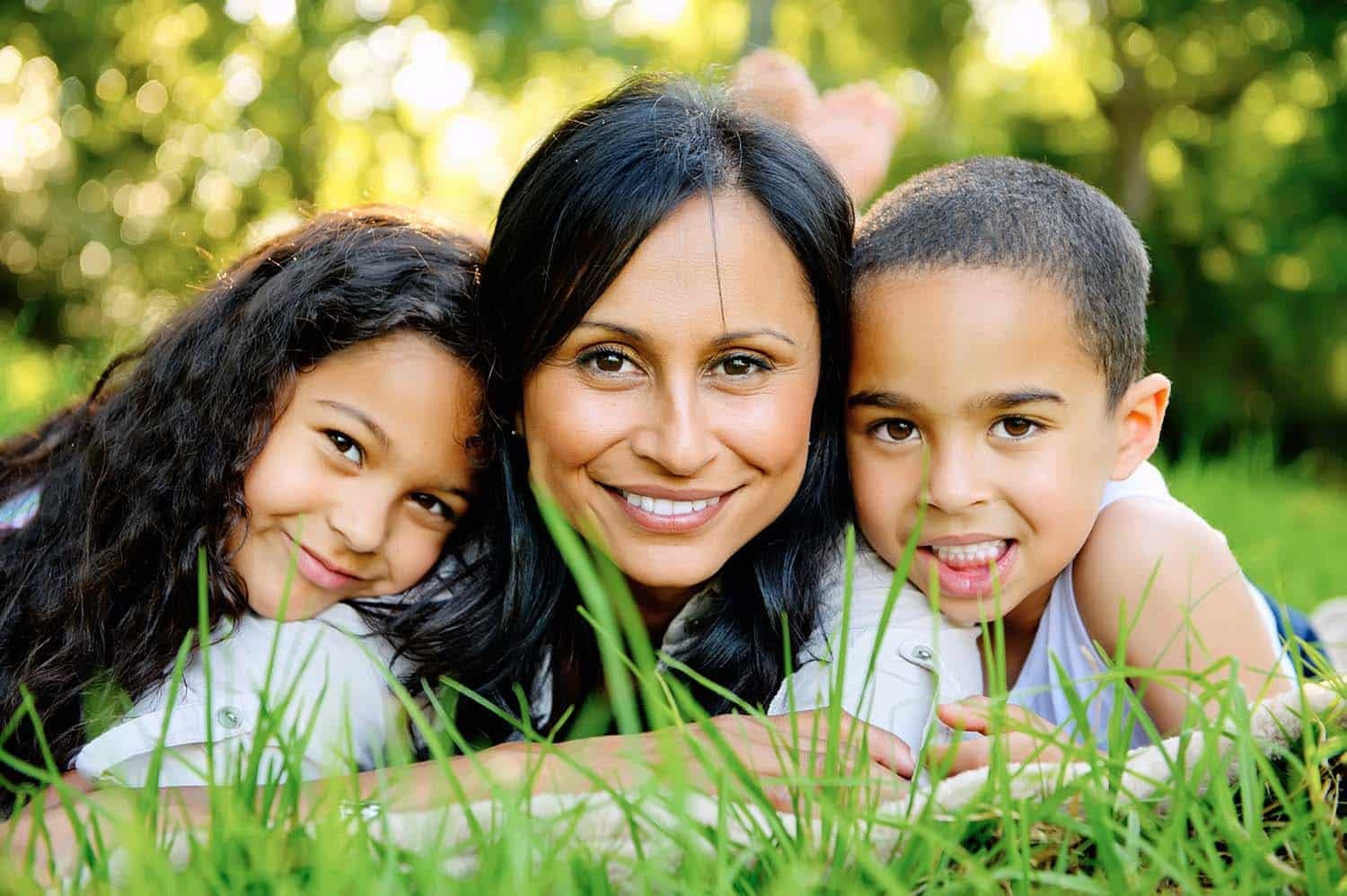 Happy mother and two children smiling outdoors in Corpus Christi, Texas.