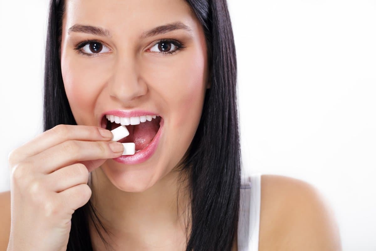 Woman chewing sugar-free gum to promote dental health and fresh breath.