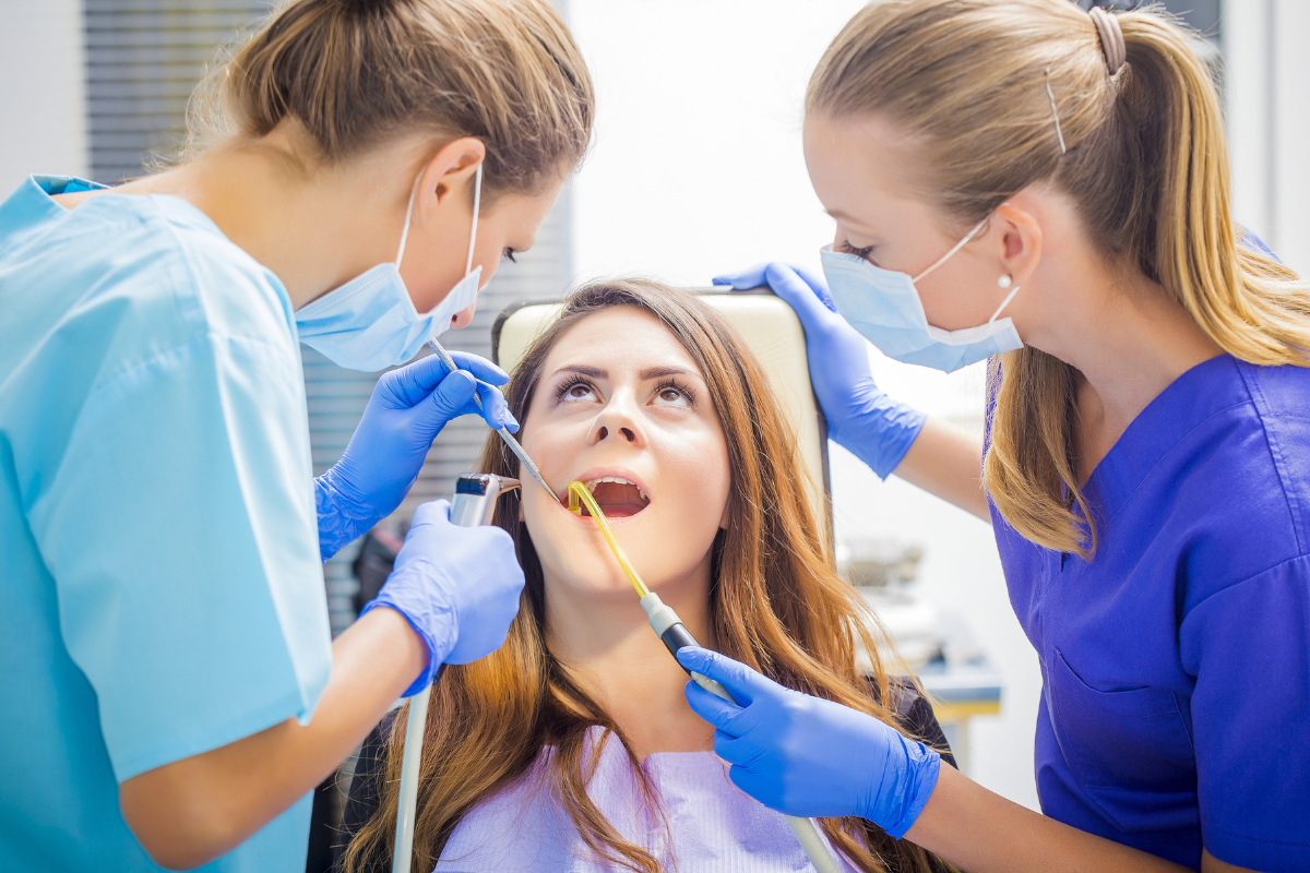 Two dental professionals examine a patient's teeth during a checkup at an emergency dentist office.