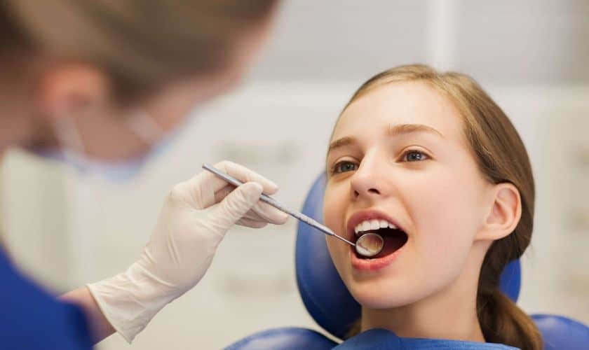 Young patient receiving dental examination during professional teeth cleaning appointment.