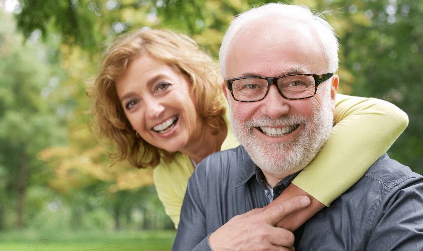 Smiling mature couple enjoying time together in outdoor garden setting.