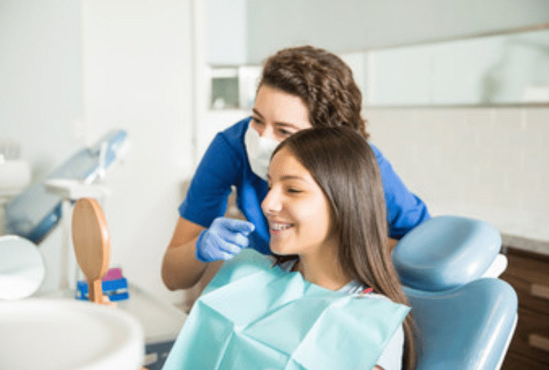 Female orthodontist examining young patient's smile in dental chair at Corpus Christi practice.