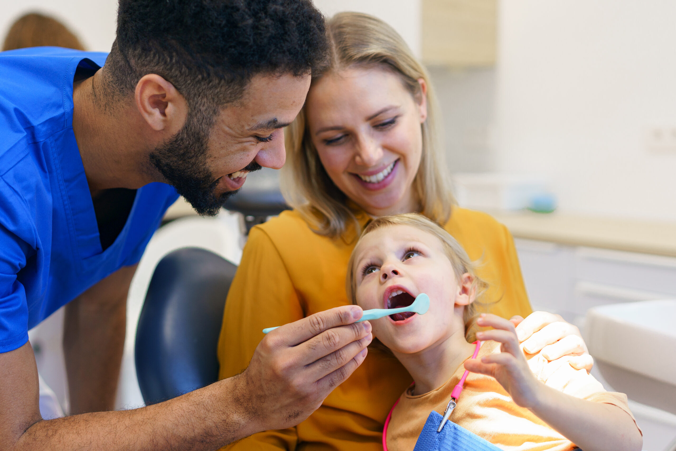 Dentist examining young child's teeth during family dental visit in Corpus Christi.