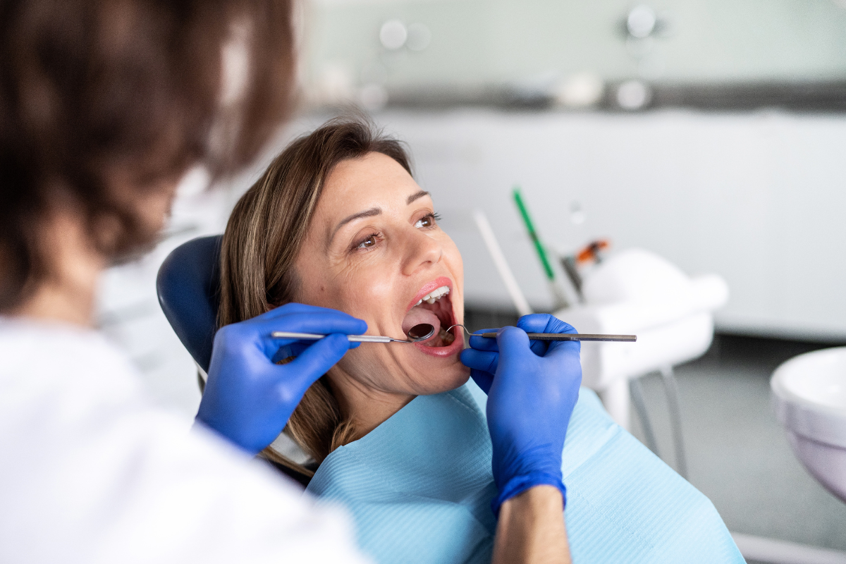 Dentist examining patient's teeth during orthodontic treatment at dental office.