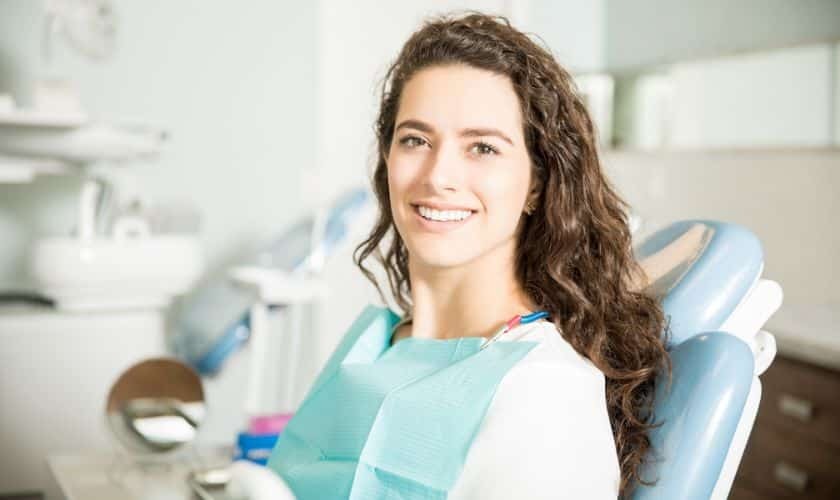 Smiling woman in dental bib seated in treatment chair at Corpus Christi dental office.