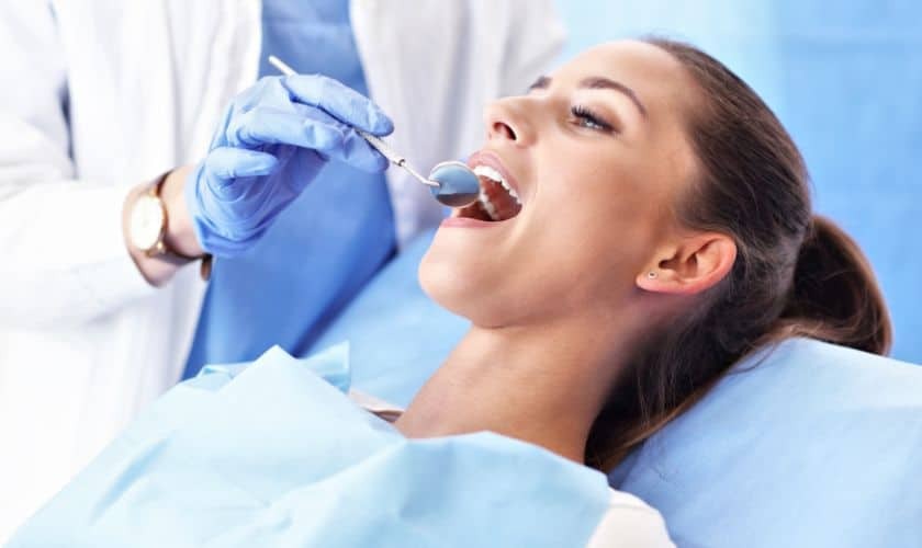 Dentist performing root canal examination on patient in dental chair.