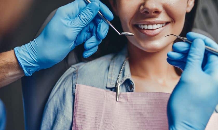 Smiling patient receiving comfortable dental examination from dentist wearing blue gloves.