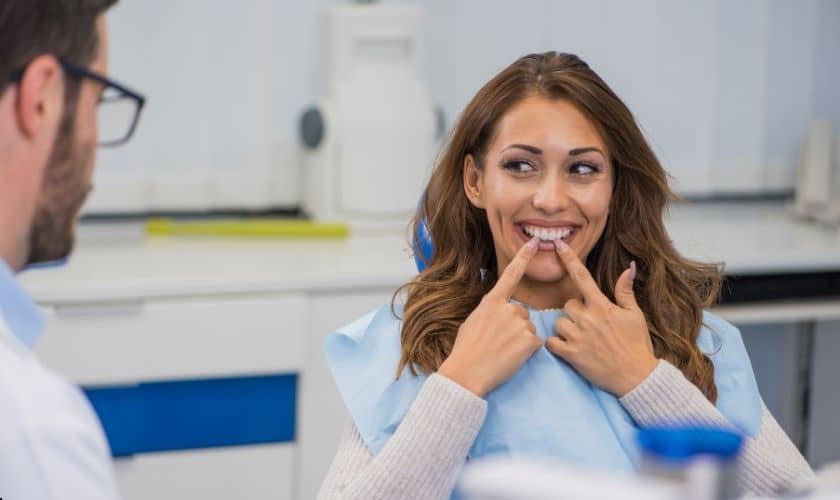 Patient pointing to her smile while discussing sedation dentistry options with dentist.
