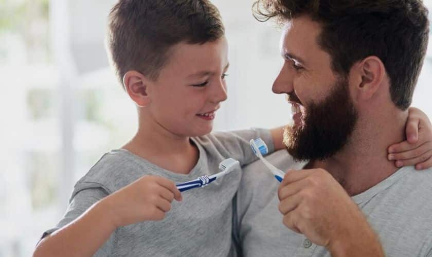 Father and son brushing teeth together, promoting family dental care and oral hygiene habits.