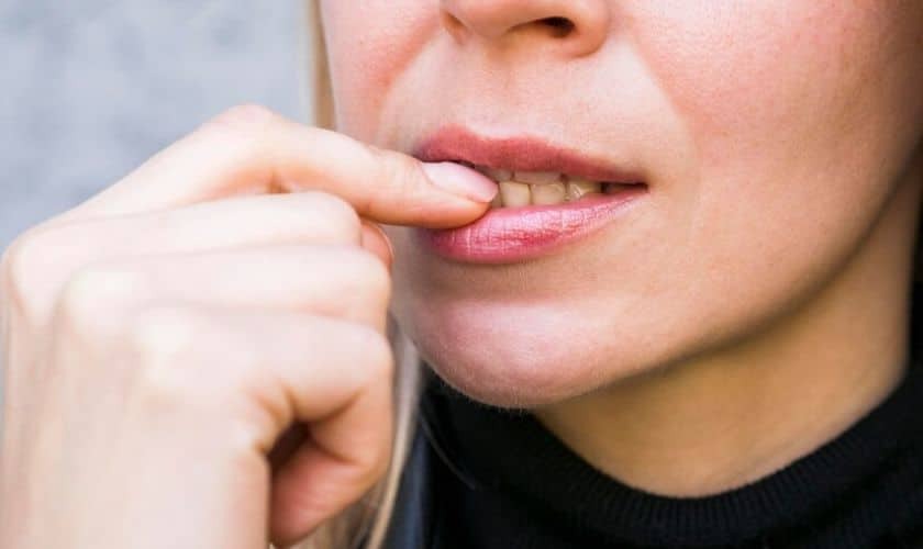 Woman pointing to her gum area, showing signs of gum disease symptoms.