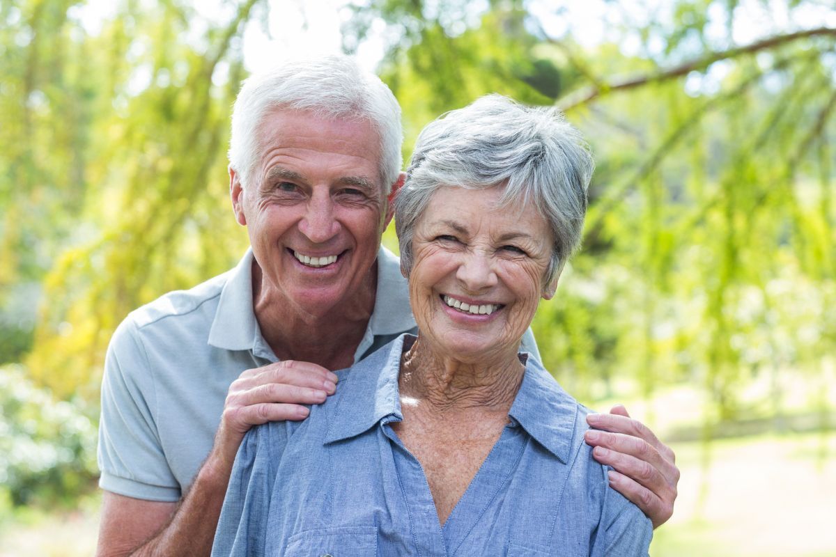 Happy senior couple smiling outdoors in Corpus Christi, showcasing dental implant results.