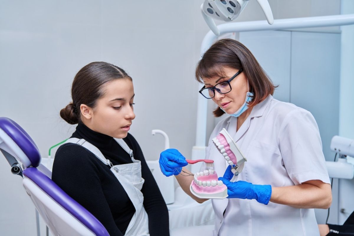 Female dentist demonstrating proper brushing technique on dental model to patient in Corpus Christi office.