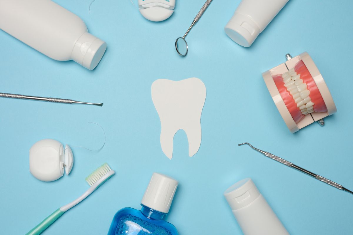 Dental tools and products arranged around a white tooth model on blue background.