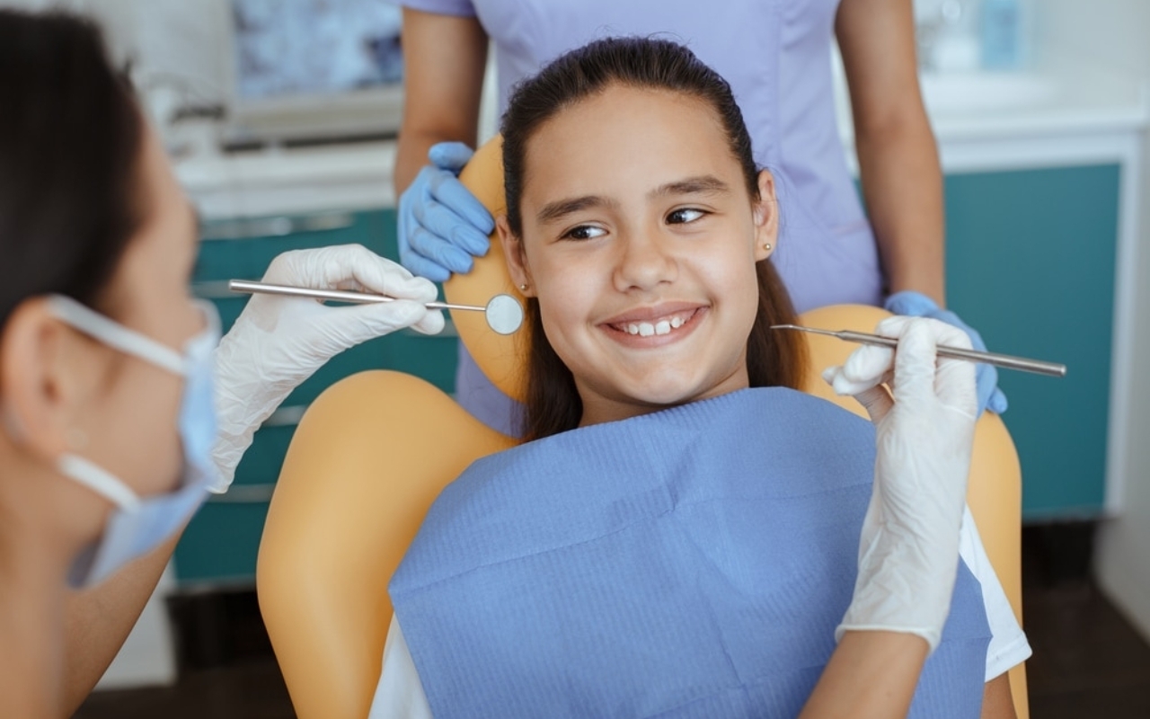 Young girl smiling in dental chair during examination by pediatric dentist in Corpus Christi.