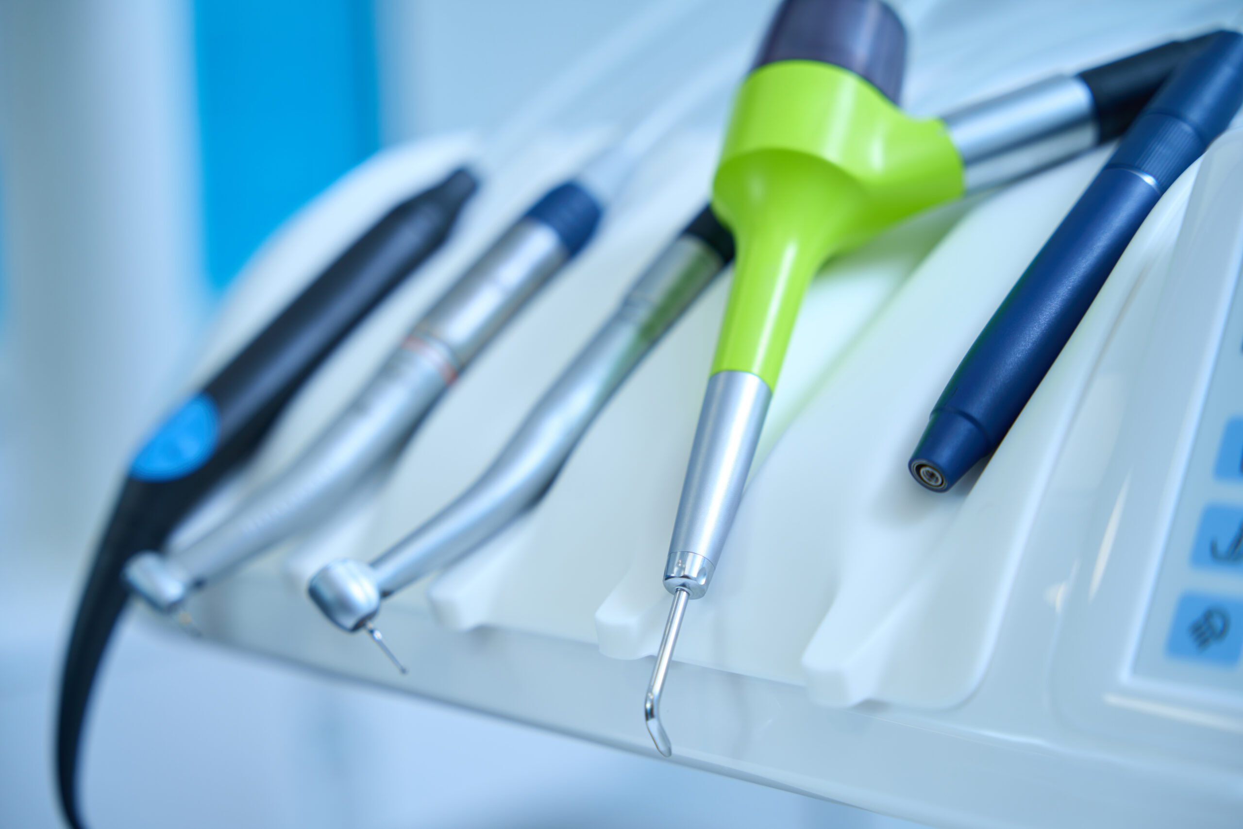 Dental instruments including a green scaler and various hand tools arranged in a tray.