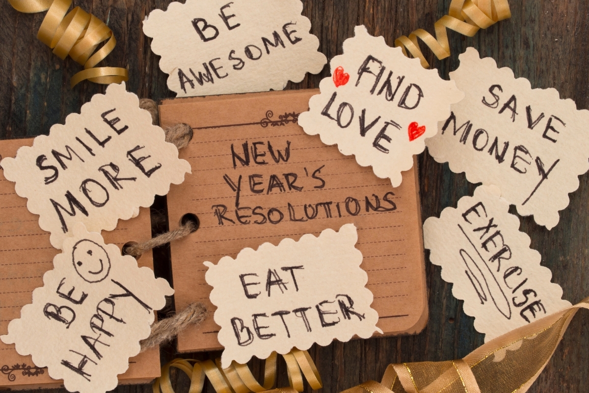 New Year's resolutions for dental health including smile more, eat better, and find love displayed on notebook.
