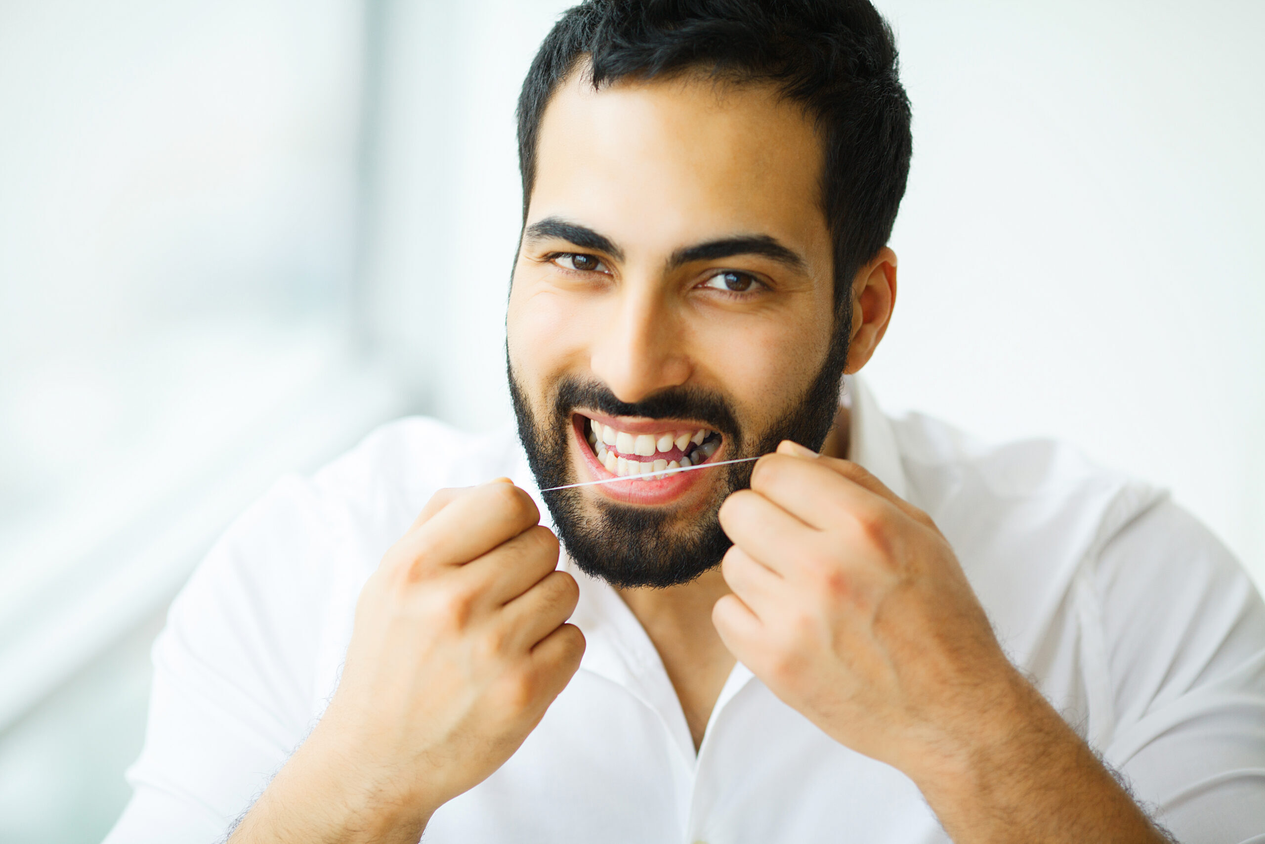 Man flossing teeth with dental floss to maintain oral hygiene.