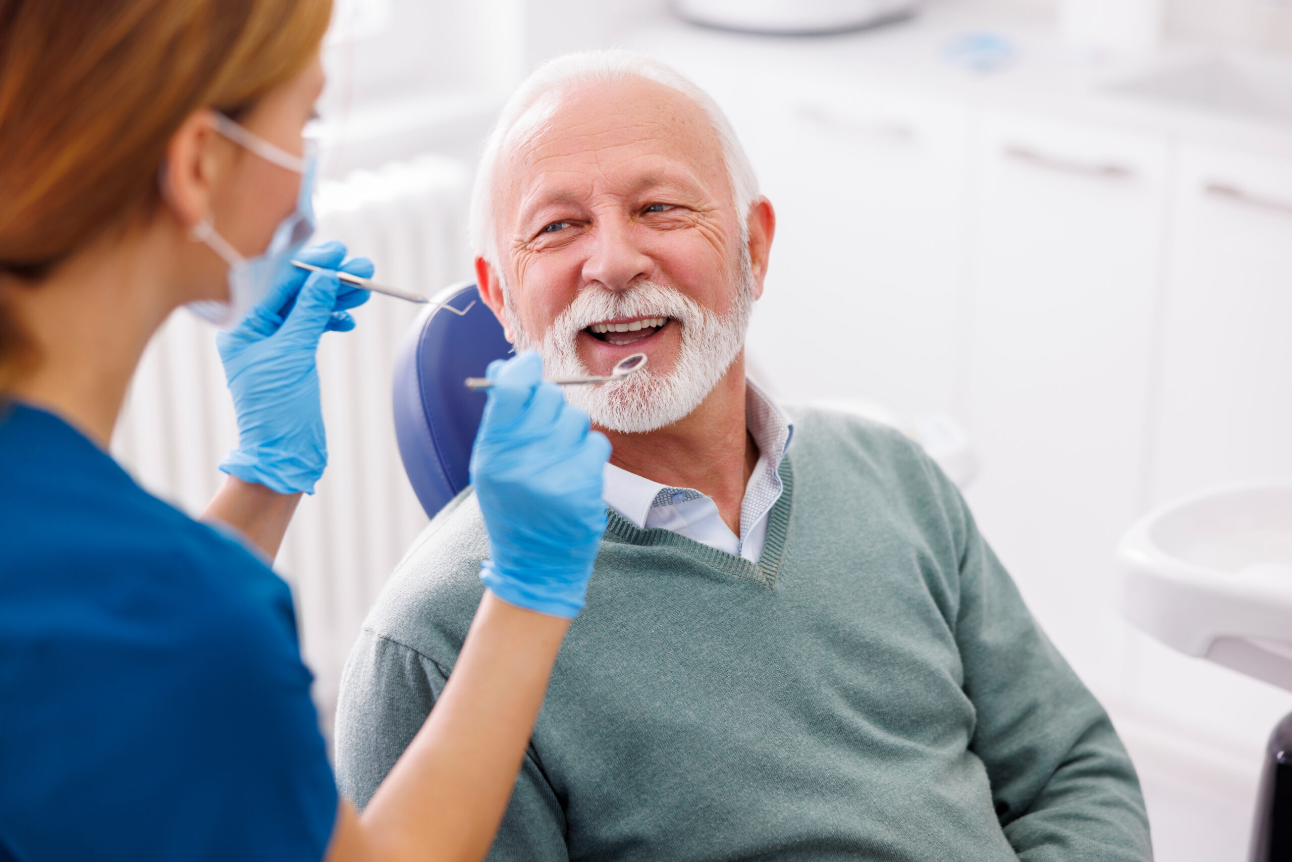 Senior man smiling during dental examination by female dentist in Corpus Christi office.