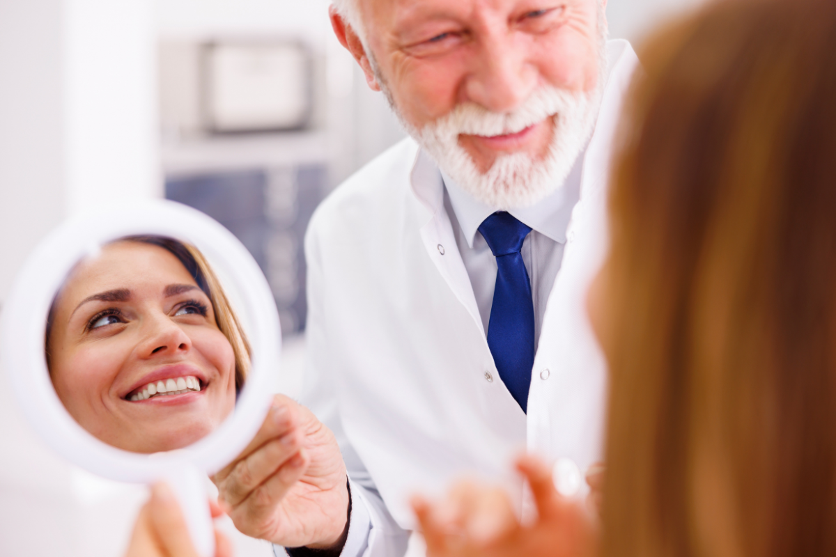 Dentist showing patient mirror reflection of healthy smile after treatment in Corpus Christi.