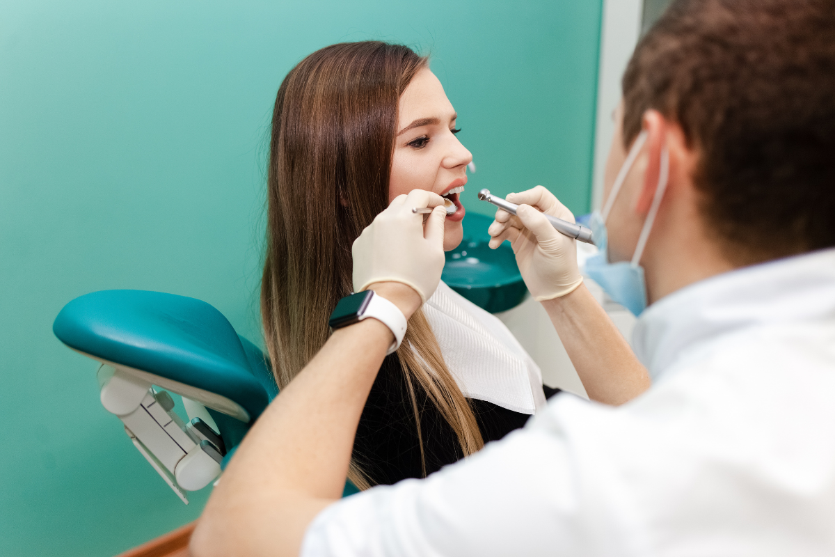 Dentist examining patient's mouth during oral health assessment in dental office.