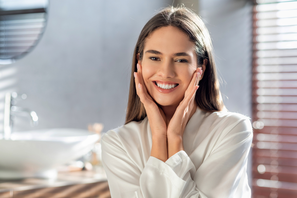 Happy woman in dental office smiling with hands to face, demonstrating oral health and dental care benefits.